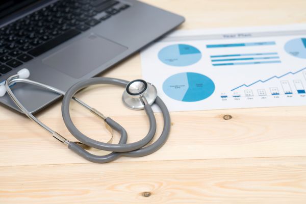 Laptop with stethoscope and financial reports on a doctor's desk