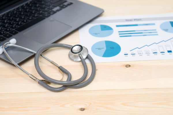Laptop with stethoscope and financial reports